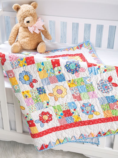You'll find the pattern for making this charming baby quilt in a lovely new pattern book called Farmhouse-Style Quilting, published by Annie's. This is an intermediate quilting pattern that requires basic piecing techniques plus fusible applique and the skills to make prairie points.  If you haven't yet mastered these techniques, you'll have a chance to practice them when you make this pretty baby quilt.